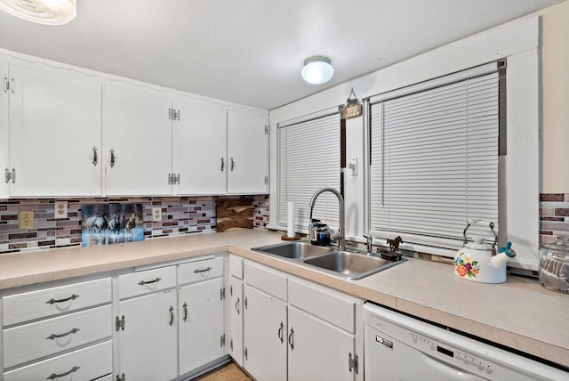 kitchen with white dishwasher, white cabinets, sink, and tasteful backsplash