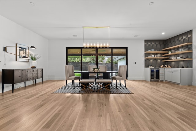 dining room with bar area, beverage cooler, and light wood-type flooring