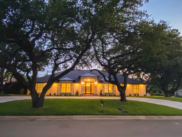 view of front of home with curved driveway and a front yard