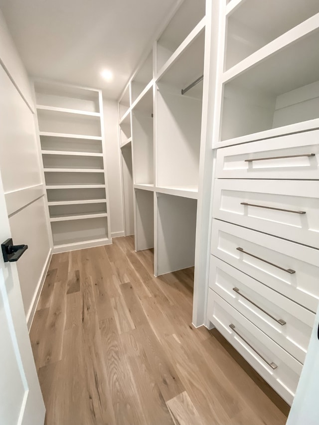 walk in closet with light hardwood / wood-style floors