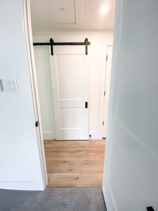 hall with wood-type flooring and a barn door