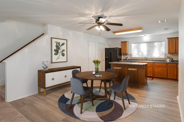 dining space featuring sink, ceiling fan, and light wood-type flooring