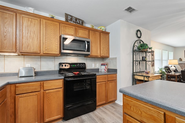 kitchen with black electric range, light wood-type flooring, and decorative backsplash