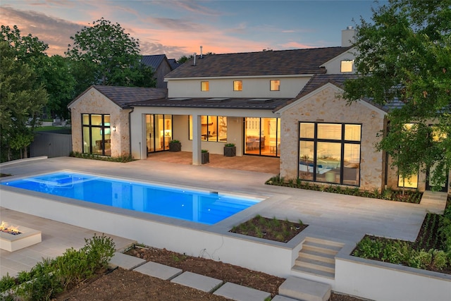 455 Sun Vly, Mabank, TX 75147 - back of property at dusk with a standing seam roof, a patio, an outdoor pool, an outdoor fire pit, and metal roof
