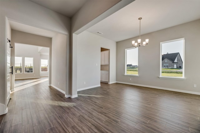 spare room with dark hardwood / wood-style flooring and a notable chandelier