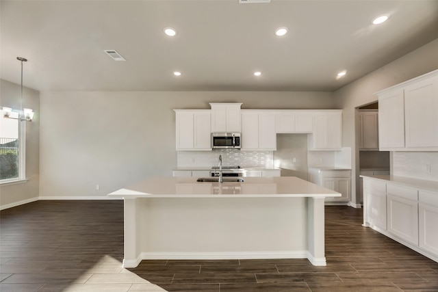 kitchen featuring sink, hanging light fixtures, dark hardwood / wood-style flooring, an island with sink, and white cabinets