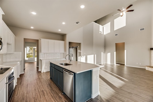 kitchen with stainless steel appliances, white cabinetry, a kitchen island with sink, and sink