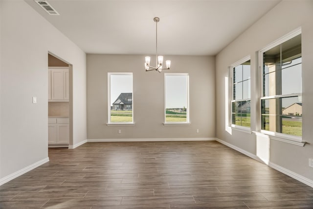 unfurnished dining area featuring a chandelier and dark hardwood / wood-style floors