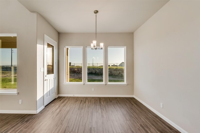 unfurnished dining area with dark hardwood / wood-style flooring and an inviting chandelier