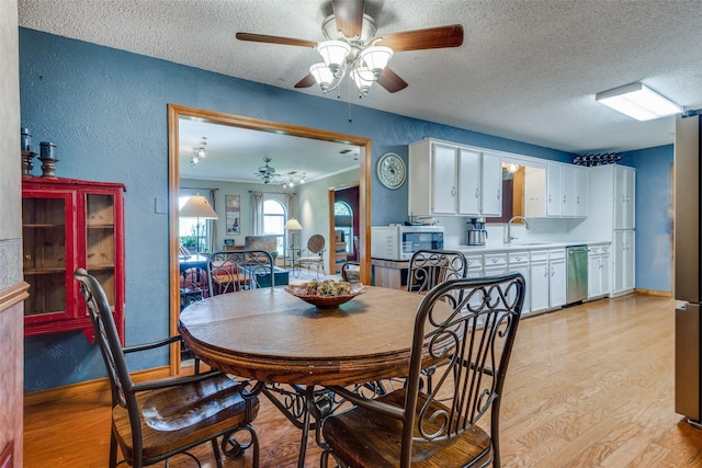 dining space with ceiling fan, sink, light hardwood / wood-style floors, and a textured ceiling