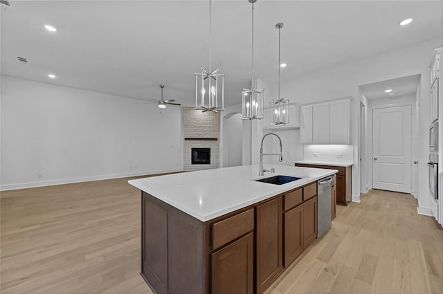 kitchen featuring light wood-type flooring, a center island with sink, white cabinetry, and sink