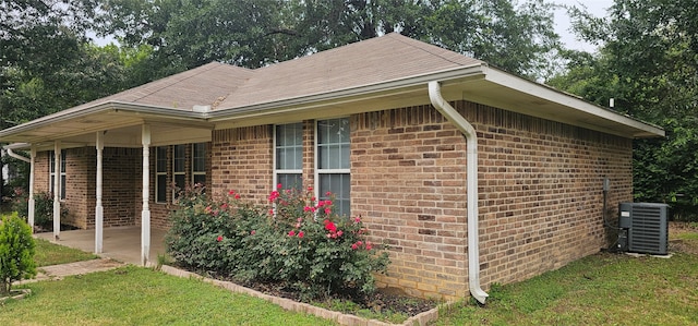 view of side of property with a yard and central air condition unit