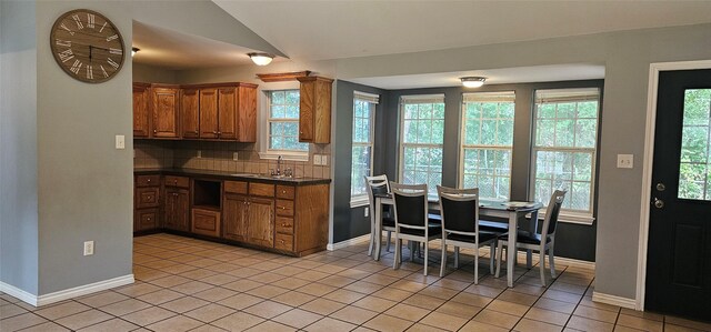 kitchen featuring baseboards, light tile patterned floors, dark countertops, and a sink