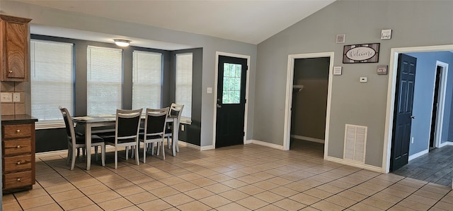 dining space with light tile floors and lofted ceiling