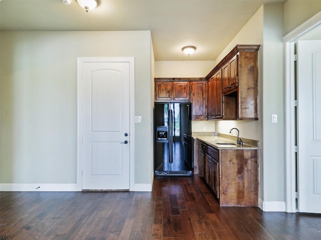 kitchen with dark hardwood / wood-style flooring, black fridge with ice dispenser, and sink