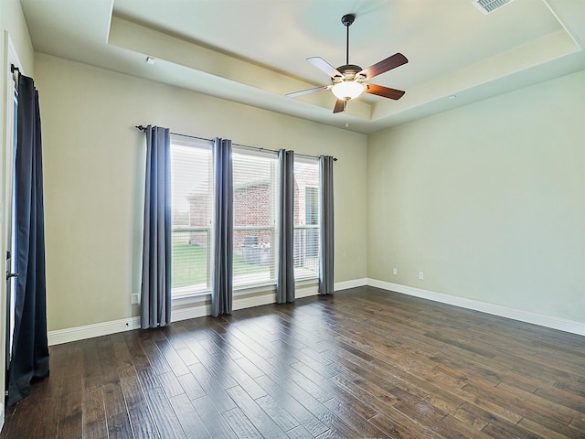 spare room featuring ceiling fan, dark wood-type flooring, and a tray ceiling