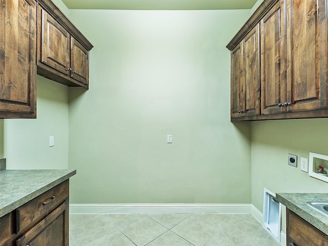 clothes washing area featuring electric dryer hookup, hookup for a washing machine, light tile patterned floors, and cabinets