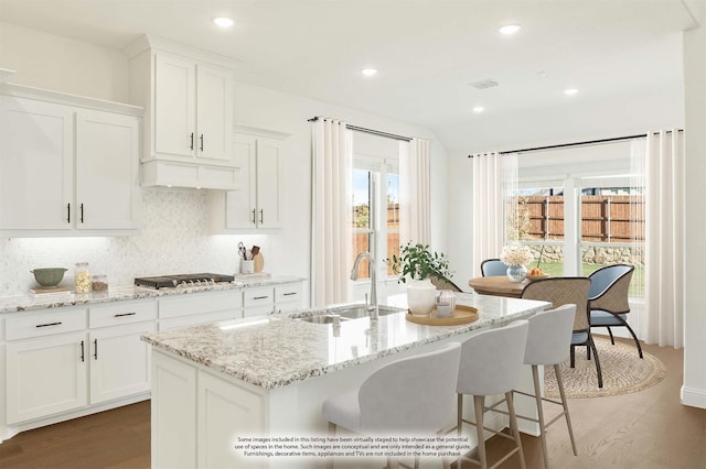 kitchen featuring white cabinetry, sink, a kitchen island with sink, and decorative backsplash