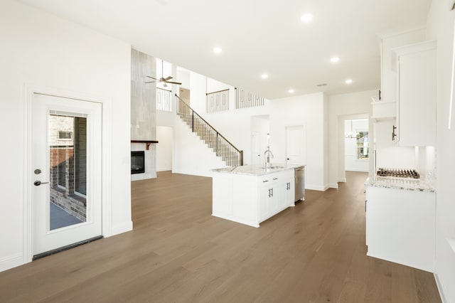 kitchen with sink, white cabinetry, light stone counters, wood-type flooring, and dishwasher