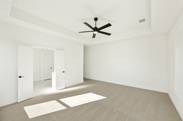 carpeted empty room featuring ceiling fan and a tray ceiling