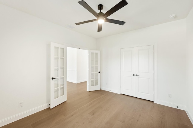 unfurnished bedroom featuring french doors, ceiling fan, a closet, and light wood-type flooring