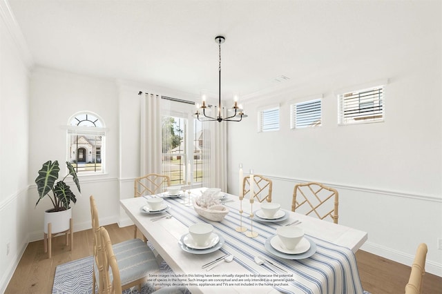 dining space featuring wood-type flooring, a notable chandelier, and crown molding