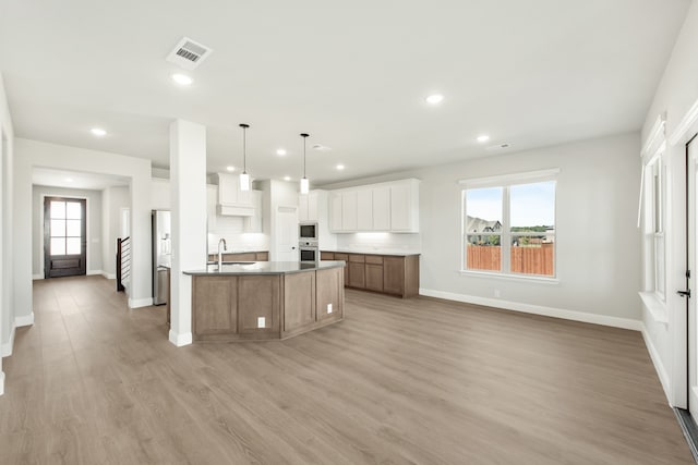 kitchen featuring a large island with sink, white cabinetry, sink, and a wealth of natural light