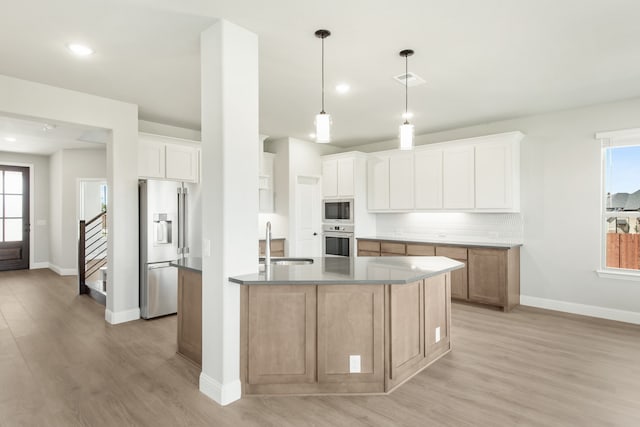 kitchen featuring a large island, stainless steel appliances, a healthy amount of sunlight, and white cabinetry