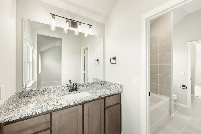 bathroom featuring tile patterned flooring, lofted ceiling, a tub to relax in, vanity, and toilet