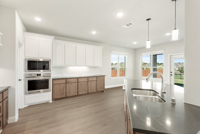 kitchen with white cabinets, sink, light hardwood / wood-style flooring, stainless steel oven, and built in microwave