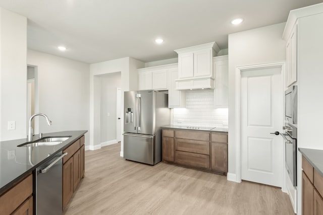 kitchen with appliances with stainless steel finishes, light hardwood / wood-style floors, sink, and white cabinets