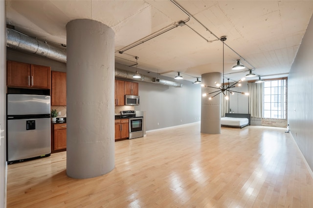 basement featuring an inviting chandelier, light hardwood / wood-style flooring, and stainless steel refrigerator