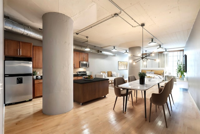 dining area with expansive windows, an inviting chandelier, and light hardwood / wood-style floors