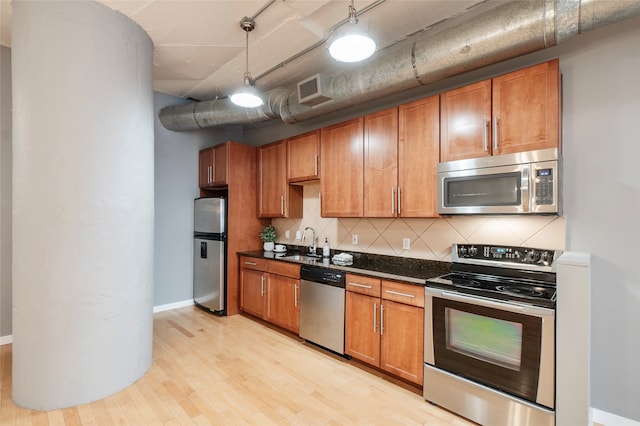 kitchen featuring sink, hanging light fixtures, decorative backsplash, light hardwood / wood-style floors, and stainless steel appliances