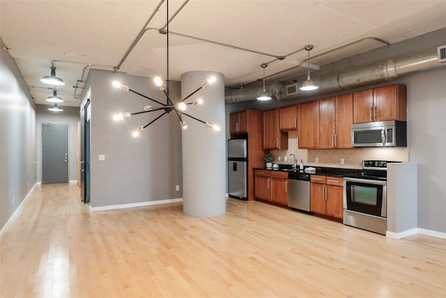 kitchen featuring pendant lighting, decorative backsplash, appliances with stainless steel finishes, a notable chandelier, and light hardwood / wood-style floors