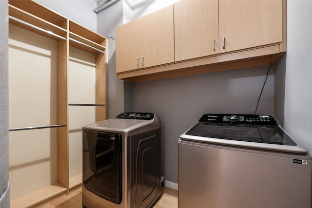 clothes washing area with cabinets and separate washer and dryer