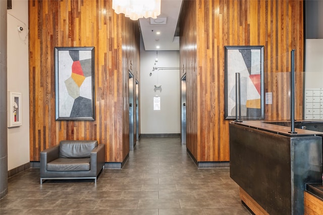 corridor with wood walls, a towering ceiling, and an inviting chandelier