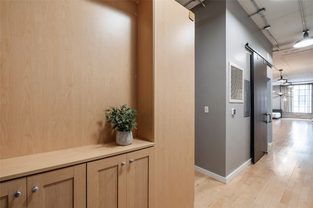 corridor featuring a barn door and light hardwood / wood-style flooring