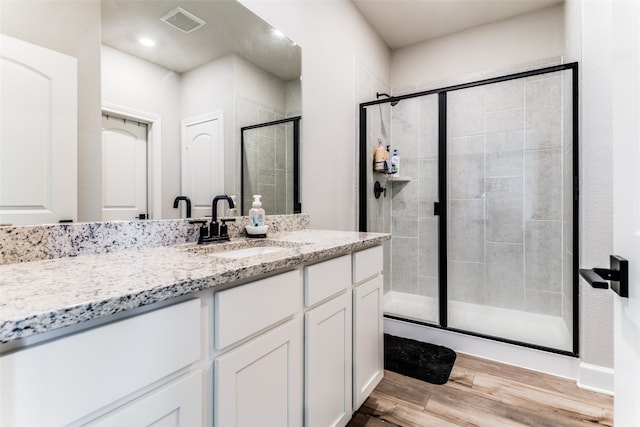 bathroom featuring a shower with shower door, vanity, and hardwood / wood-style floors