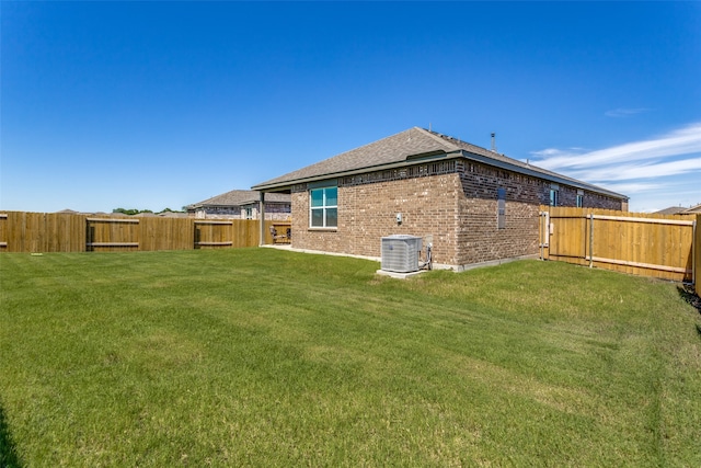 rear view of property featuring a lawn and central air condition unit