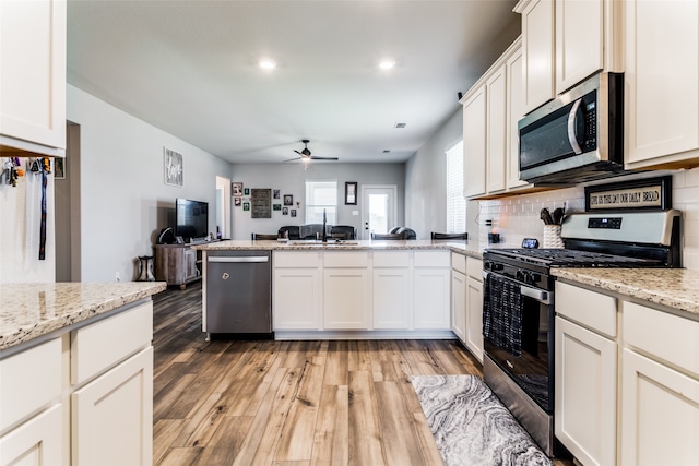 kitchen with light stone countertops, stainless steel appliances, hardwood / wood-style floors, tasteful backsplash, and ceiling fan