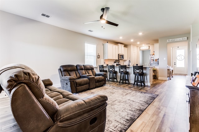 living room featuring light hardwood / wood-style floors, a wealth of natural light, sink, and ceiling fan