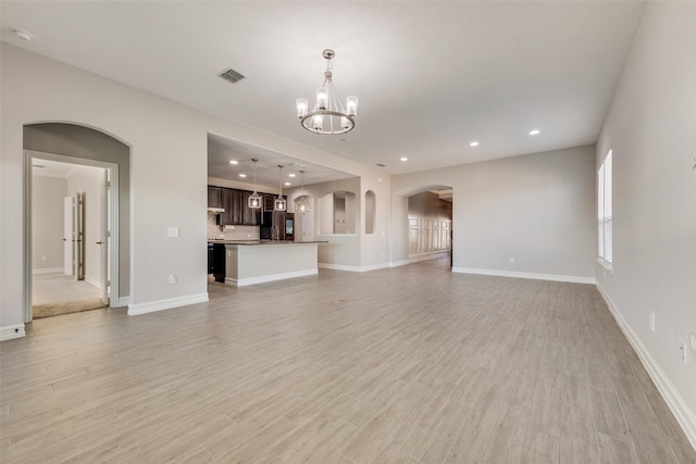 unfurnished living room with a chandelier and light hardwood / wood-style floors