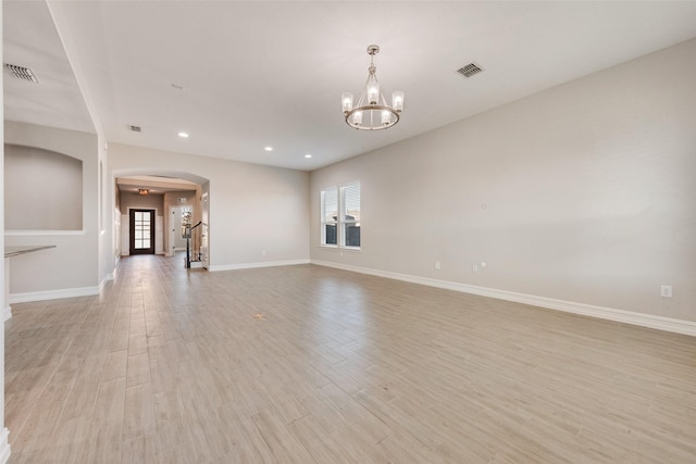 empty room featuring an inviting chandelier and light wood-type flooring