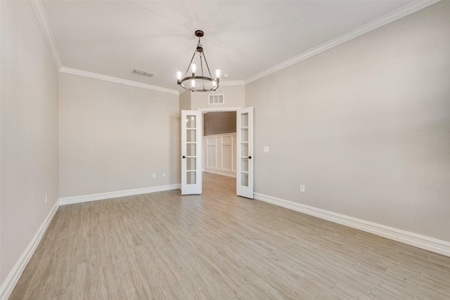 spare room with crown molding, an inviting chandelier, light wood-type flooring, and french doors