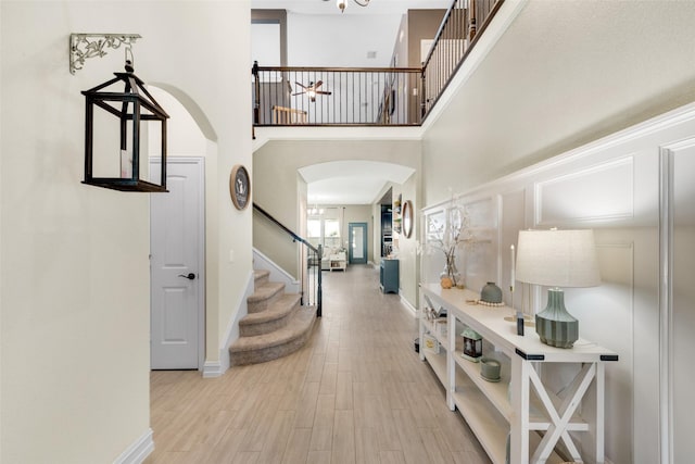 foyer with a towering ceiling and light wood-type flooring