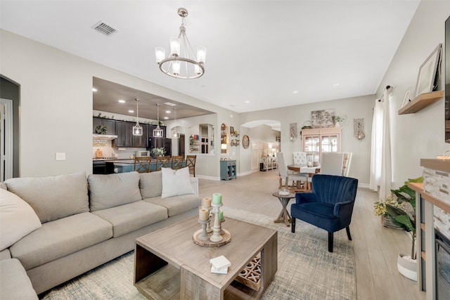 living room featuring a notable chandelier, light wood-type flooring, and a fireplace