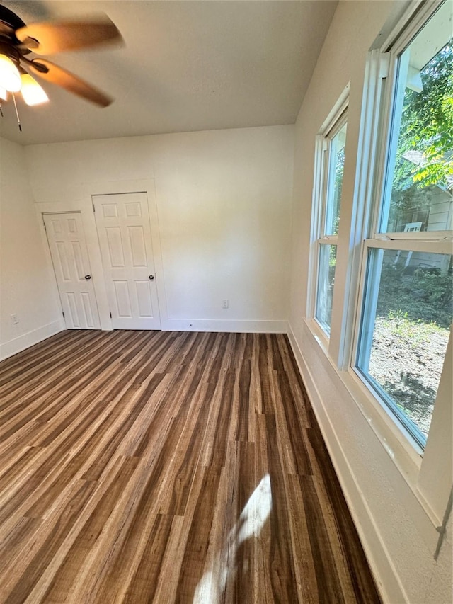 spare room with dark wood-style floors, plenty of natural light, baseboards, and ceiling fan