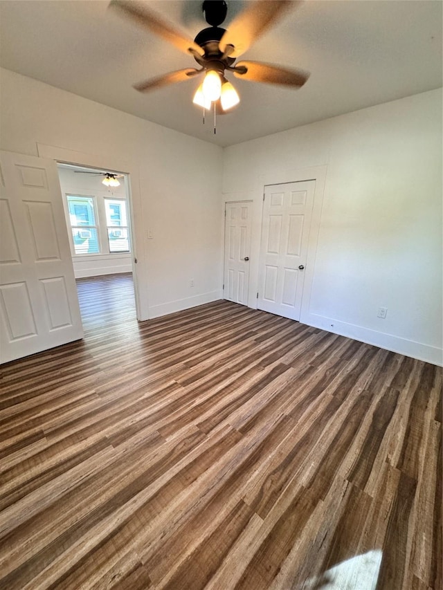 spare room featuring dark wood-style floors, a ceiling fan, and baseboards