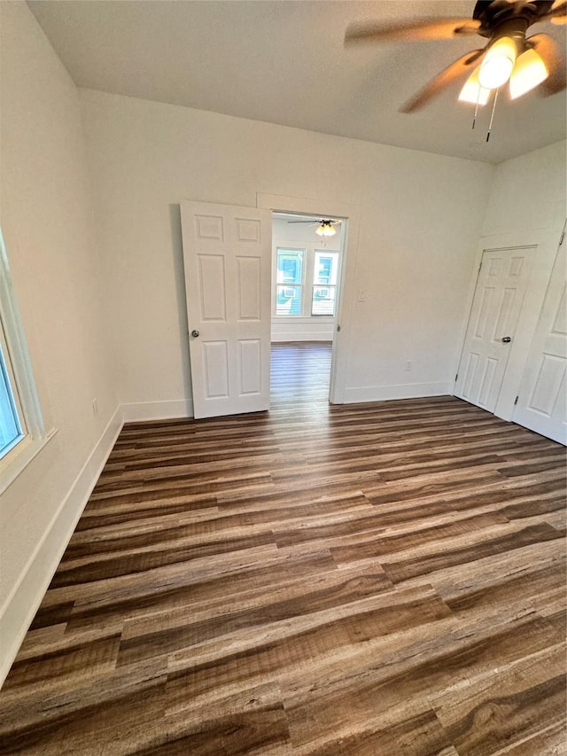 spare room with baseboards, dark wood finished floors, and a ceiling fan